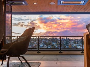A chair is in the foreground of a room with a view of a cityscape at sunset.at Axle, Seattle Washington